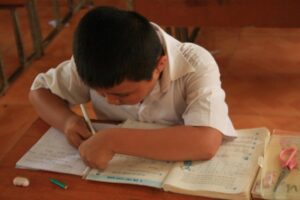 A young Vietnamese boy focused on writing during class, embodying concentration and educational dedication.